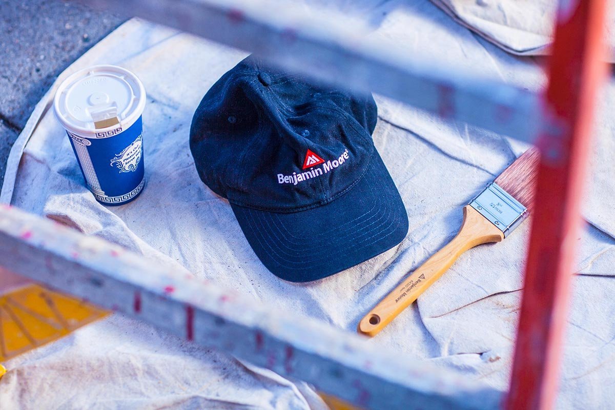 Blue Benjamin Moore baseball cap, Benjamin Moore paint brush, and coffee. Work is enjoyable when you are rewarded with free stuff!
