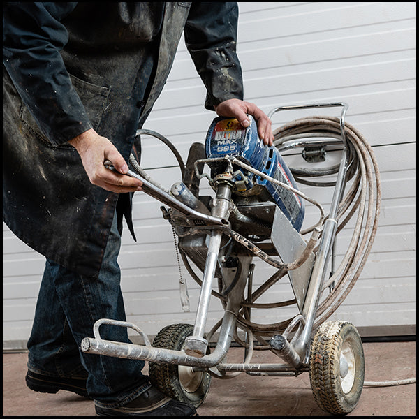 A man with a Graco paint sprayer, available at Clement's Paint in Austin, TX.